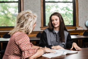 two women siting at a table discussing book in front of them