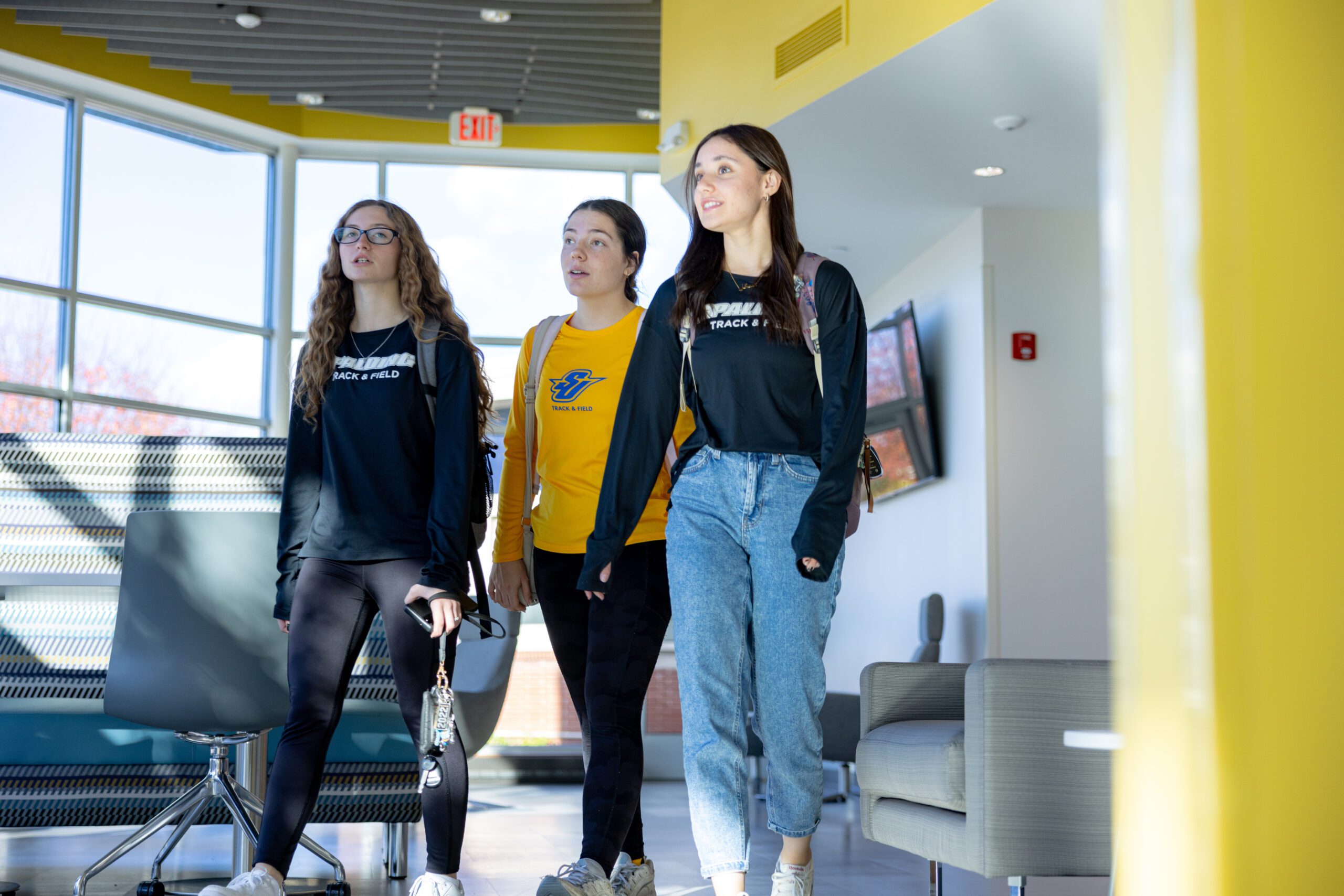 three female students walking through scool atrium