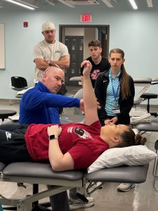 Occupational therapy professor demonstrates a technique on a student in an OT lab
