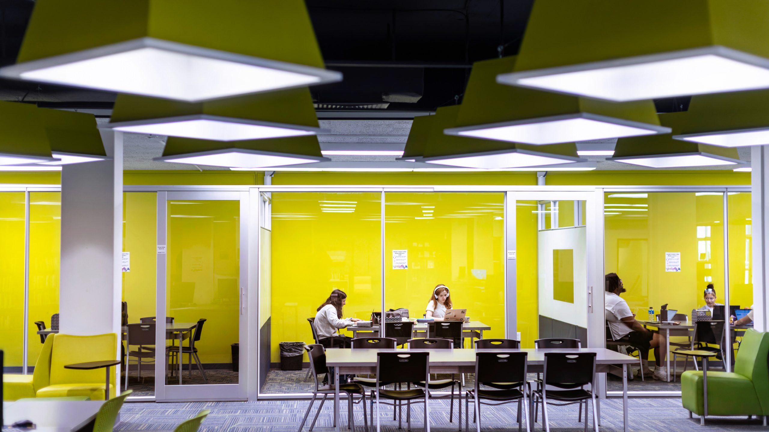 students sitting at desk with bright yellow wall in background
