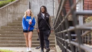 A black male and a white female Spalding student walk outdoors on the Spalding campus