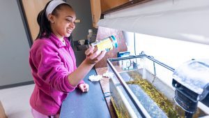 Black female student works at an aquarium in a science lab setting