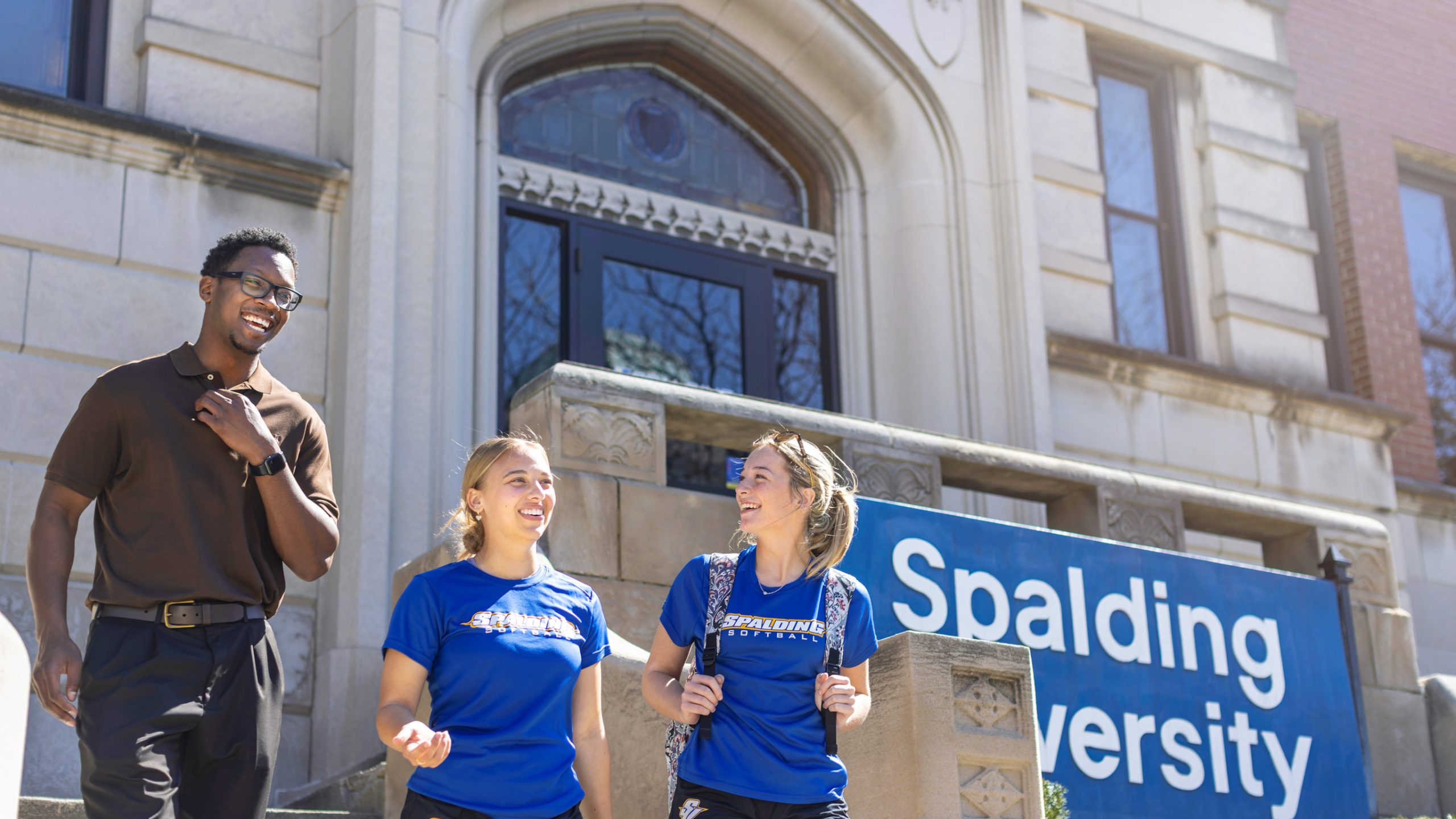 three students laughing outside Spalding University building