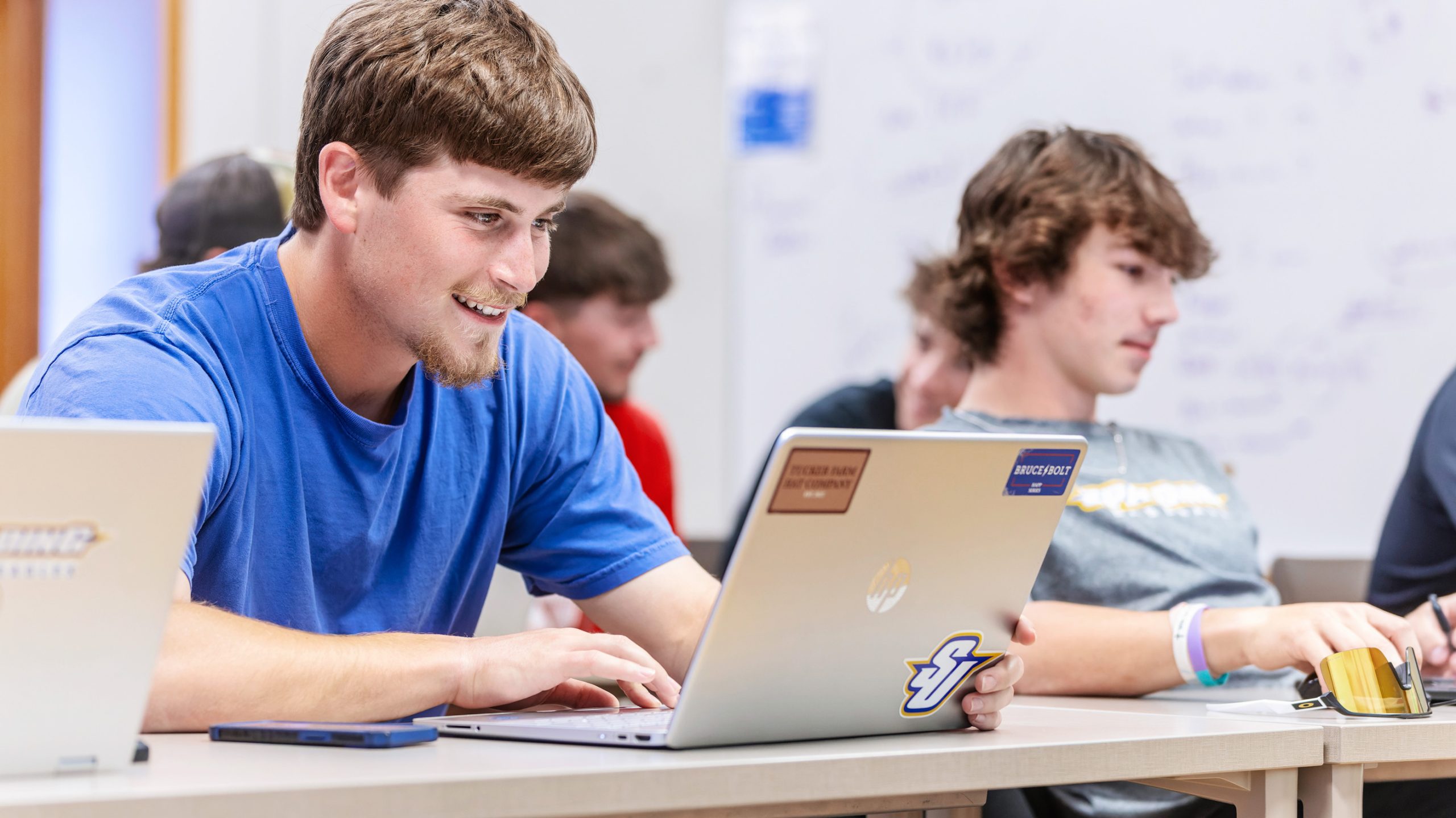 male student smiling while looking at laptop during class