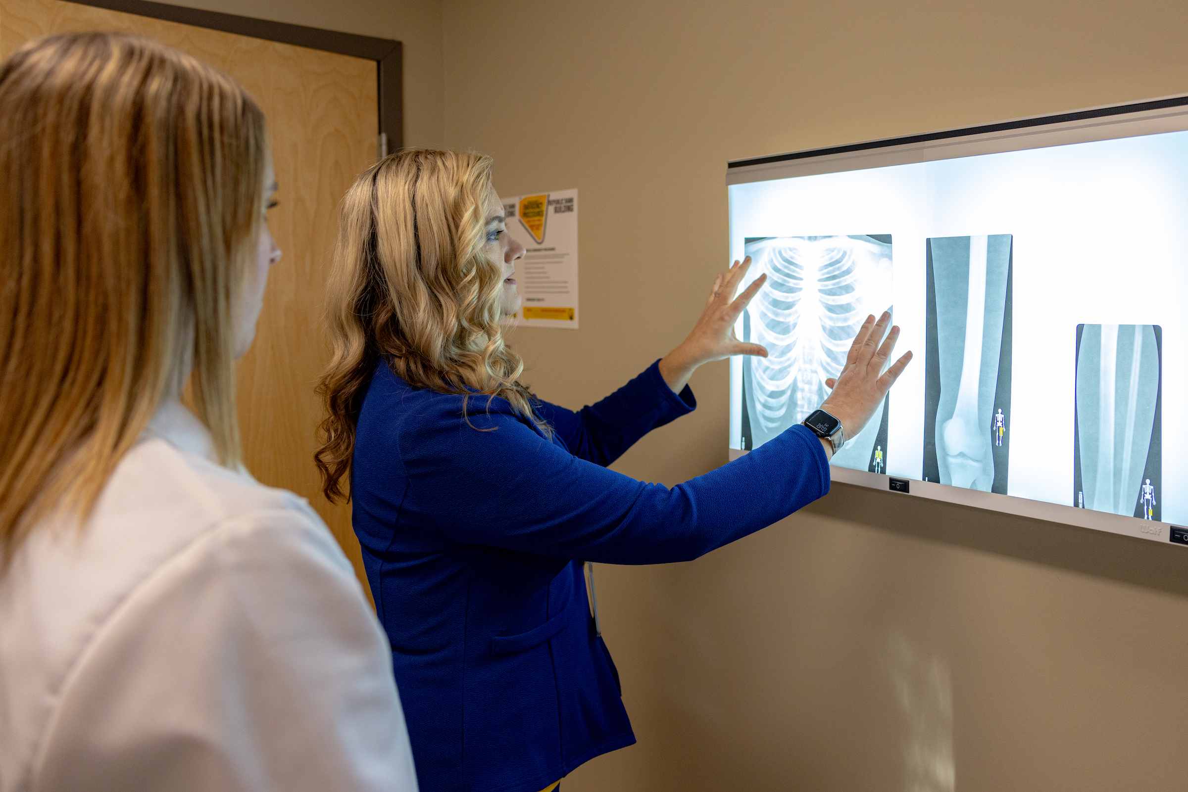 Nursing professor examines x-ray with student looking on