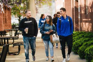 Group of three students wearing Spalding gear walk together on a sidewalk