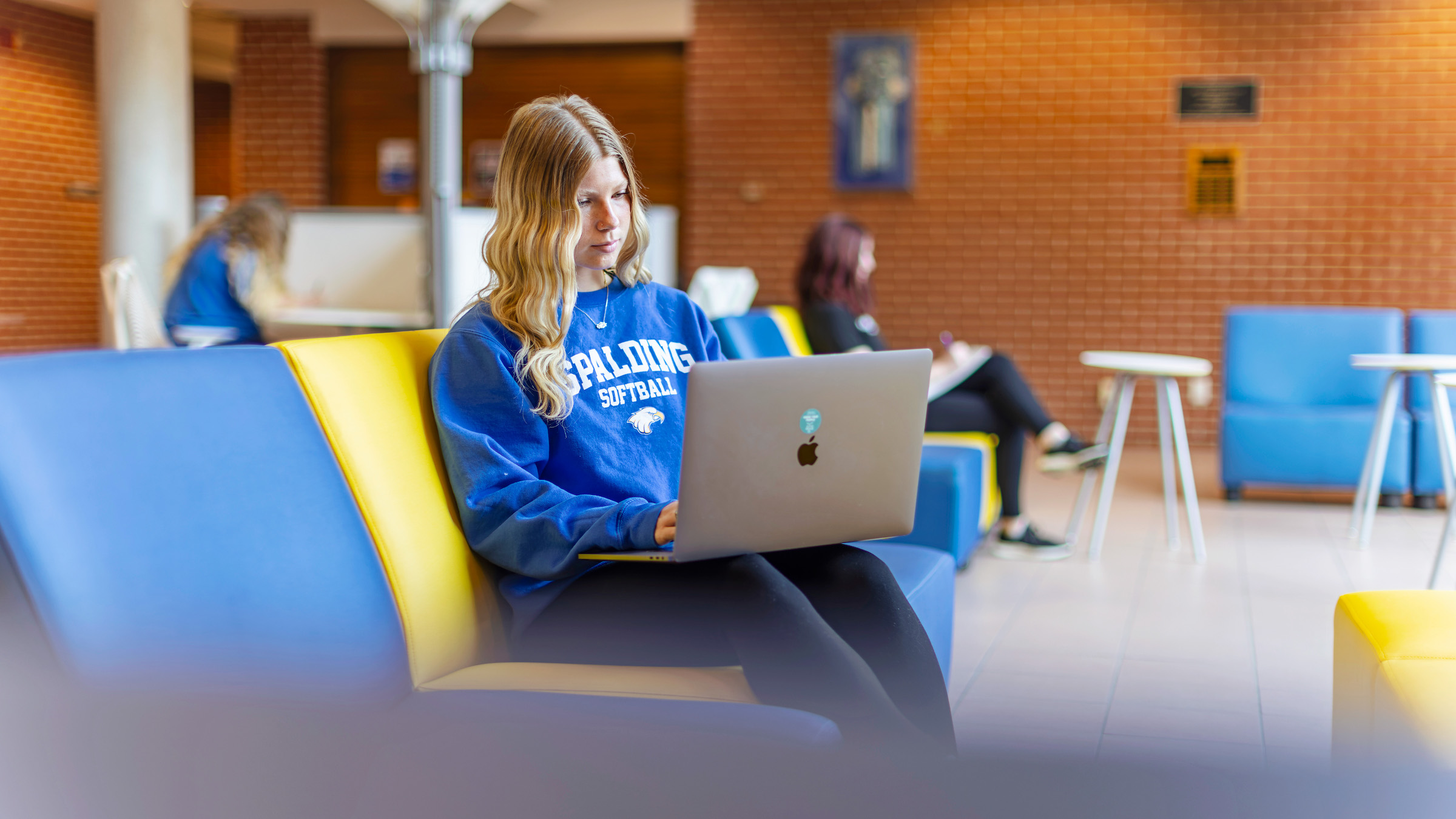 Female student with long blonde hair sits in a Spalding study space working on a laptop